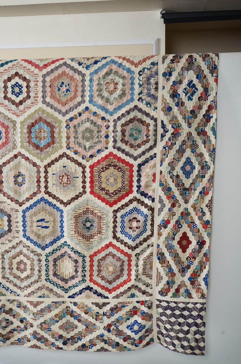A large 19th century ‘Grandmother’s Flower Garden’ cotton patchwork bedspread, using dress fabric scraps from the day to create hexagonal concentric patterns which form a flower like shape/pattern, 282 x 254cm. Condition